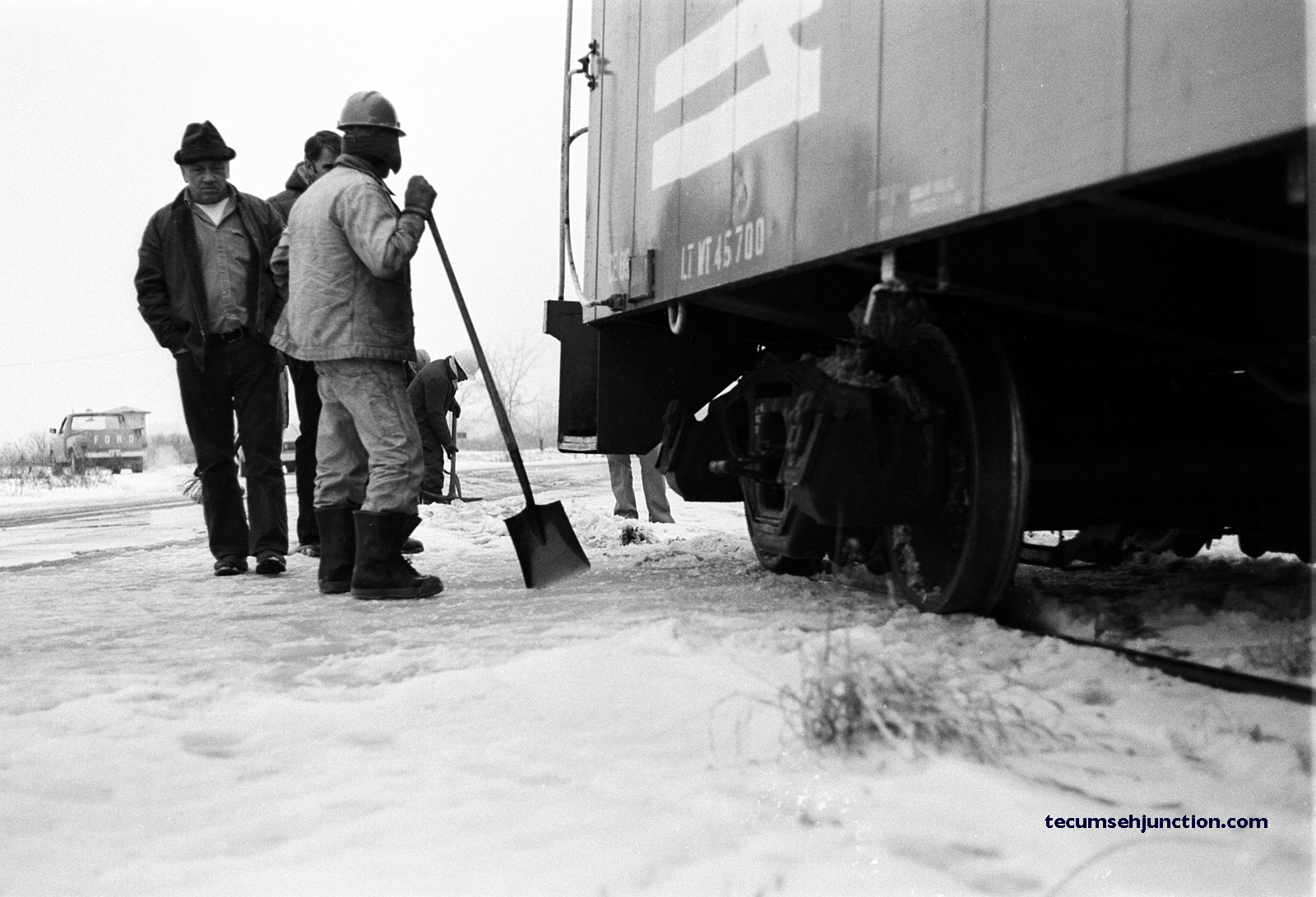 Conrail maintenance-of-way workers carefully observe as the as the caboose is backed over the Deerfield Road crossing.